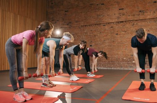 Fitness group performing exercises with dumbbells in a modern yoga studio setting.