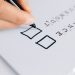 A hand drawing checkboxes on a checklist, themed around balance and burnout.
