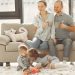Cheerful family smiling while spending weekend together sitting parents sitting on comfortable sofa while children resting on carpet and playing